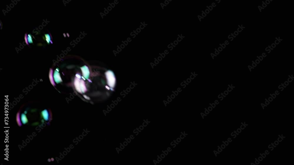 Poster colorful soap bubbles fly in empty space on isolated black background. colorful lights. many rainbow