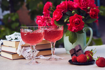 Romantic summer table settings. Couple glasses of red strawberry wine. Natural strawberry infusion. Strawberry and chocolate. Roses bouquet.