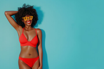 Full body portrait of a funny young happy African American woman in red swimsuit going on summer holiday trip and having fun on a blue studio background with copy space. Vacation and travel concept