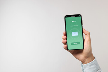 Got new message. Man holding smartphone on light grey background, closeup. Space for text