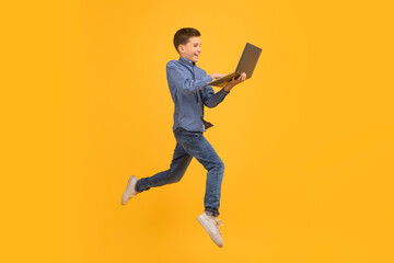 Fototapeta na wymiar Dynamic image of teenage boy jumping and holding an open laptop
