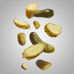 Tasty pickled cucumbers falling on light grey background