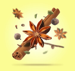 Different aromatic spices falling on yellow background