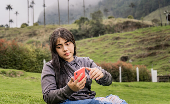retrato de mujer joven con su celular en la mano al aire libre en el parque natural