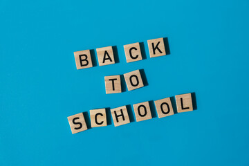 Educational greeting announcement for students and teacher. Saying BACK TO SCHOOL text on wooden blocks on colorful blue background. Top view flat lay Concept of new school year