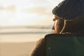 Face, thinking and man at beach at sunset to relax on holiday or vacation for travel in summer. Nature, sunshine and view with young person on coast by sea or ocean for peace and quiet from back