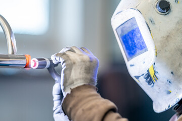 a man wearing a welding mask is welding a pipe
