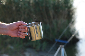 Male hand holding mug. The adventure begins travel,hiking, fishing and camping concept