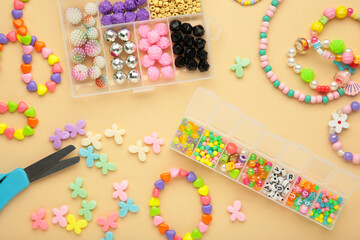 Box with beads to create hand made jewelry for child on beige background. Making bracelet. Handmade accessories.