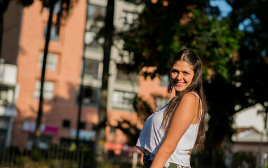 mujer latina de lado y sonriendo muy feliz mientras mira a la cámara en un parque al aire libre de...