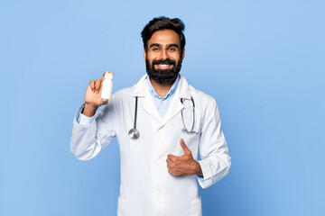 Middle aged indian male doctor holding pill bottle and giving thumbs up
