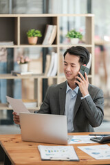 Happy asian business man have the joy of talking on the smartphone, tablet and laptop in the home office 