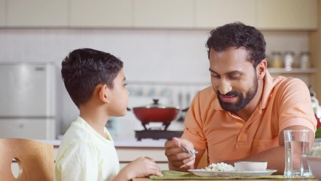 Happy father feeding His child by talking and encouraging at home - concept of fatherhood, affection and family bonding
