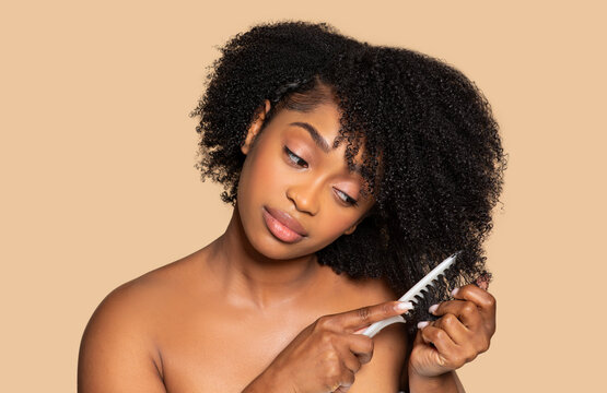 Black woman gently detangling her curly hair