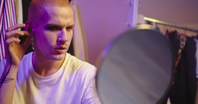 Close-Up: LGBT Individual Trying on Earrings by Large Mirror