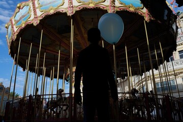 man with a balloon silhouetted against a wildly spinning carousel