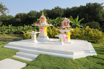 Traditional Thai spirit houses with green garden background.