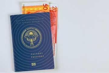 Money in Kyrgyzstan som banknotes in Kyrgyz Republic passport on white background
