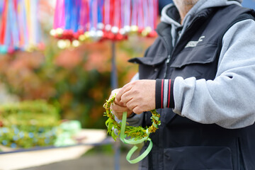 Vrbica orthodox holiday. The seller weaves a wreath for sale. Small bells, wreaths from willow...