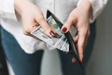 Woman's hands taking out money from wallet, dollar banknote cash