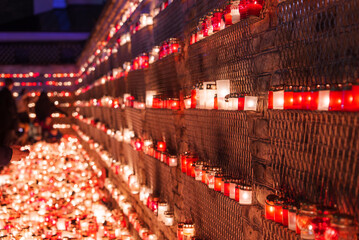 A solemn display of candles with red holders, likely for Latvia's Independence Day, emits a warm...