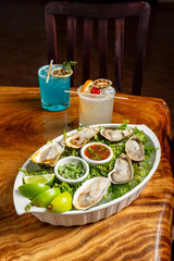 Deliciosas ostras servidas sobre lechuga con limón con dos cocteles de fondo