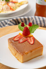 Postre flan de coco decorado con fresas en un plato con encuadre cercano