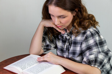 A young white woman is reading a bilingual, Polish-Hebrew edition of the Pentateuch.