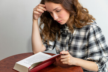 A young white woman is reading The The Book of Exodus in a bilingual, Polish-Hebrew edition of the...