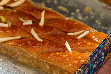 A piece of traditional Iranian baklava in the ornate metal box in which it is sold. 