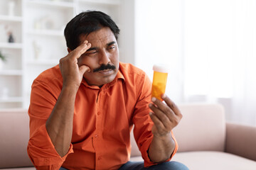 Unhealthy mature indian man suffering from migraine, taking medicine