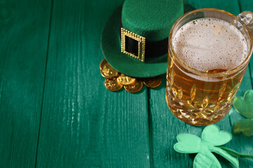 St. Patrick's day. Beer, leprechaun hat, gold and decorative clover leaves on green wooden table....