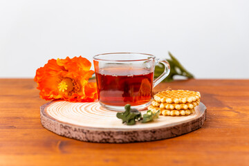 Cup of tea with biscuits next to it, on a natural wooden table.