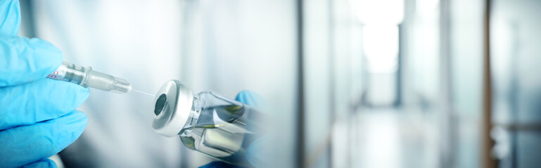 Doctor filling syringe with medication from glass vial on blurred background, closeup. Banner design