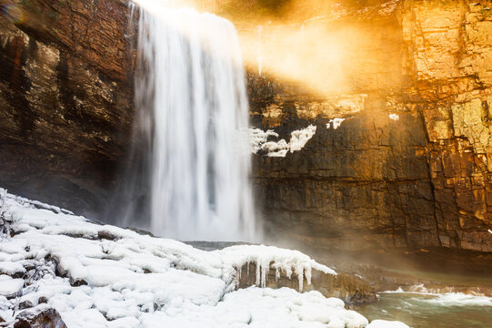 Lula Falls surrounded by icy rock in winter with golden sunlight pouring over the top, Lookout Mountain, Georgia