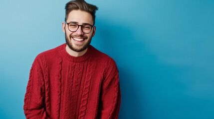 Retrato de um jovem sorridente, vestindo suéter isolado sobre fundo azul, olhando para a câmera - obrazy, fototapety, plakaty
