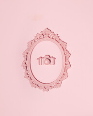 Photo camera in oval picture frame, 3d creative wall decoration, pastel pink background.