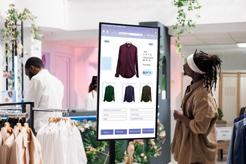 Young client search for clothes on board in clothing store boutique, self ordering interactive monitor. Trendy shopper buying modern fashion items on kiosk service display, retail store concept. - Powered by Adobe