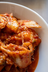 kimchi in fresh white bowl close-up on gray background
