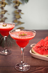 Watermelon refreshing summer frozen cocktail smoothie with watermelon slices and pieces on the background