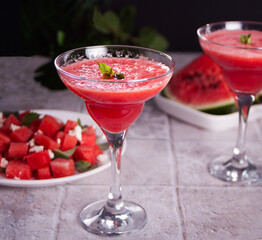 Watermelon refreshing summer frozen cocktail smoothie with watermelon slices and pieces on the background