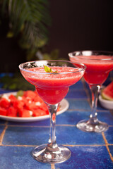 Watermelon refreshing summer frozen cocktail smoothie with watermelon slices and pieces on the background