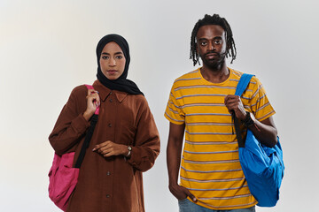 Against a clean white background, two students, an African American young man and a hijab-wearing...