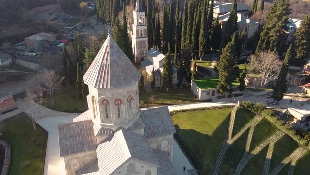 Scenic aerial view of monastic complex of Bodbe nunnery on hillside among tall Cypress trees with Church of St. Nino on sunny day, Sighnaghi, Georgia