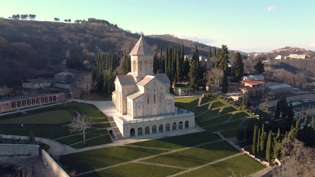 Scenic aerial view of monastic complex of Bodbe nunnery on hillside among tall Cypress trees with Church of St. Nino on sunny day, Sighnaghi, Georgia