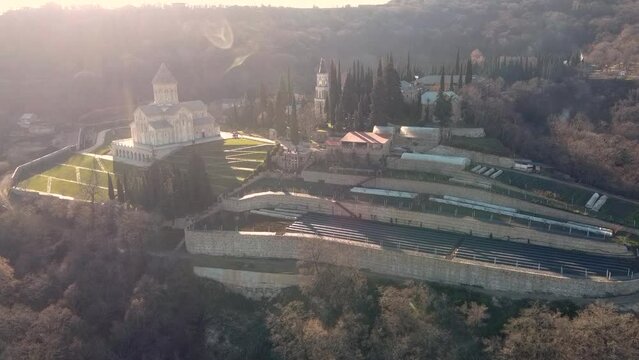 Scenic aerial view of monastic complex of Bodbe nunnery on hillside among tall Cypress trees with Church of St. Nino on sunny day, Sighnaghi, Georgia