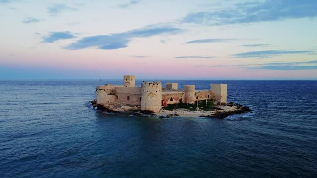 Witness the breathtaking Kizkalesi in aerial footage: a 12th-century Byzantine castle's ruins on Mersin's Mediterranean coast at sunset. Experience the architectural marvel of Kizkalesi 