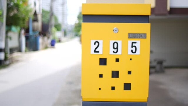 Yellow mailbox with number 295 on side of road, made of wood, rectangular shape