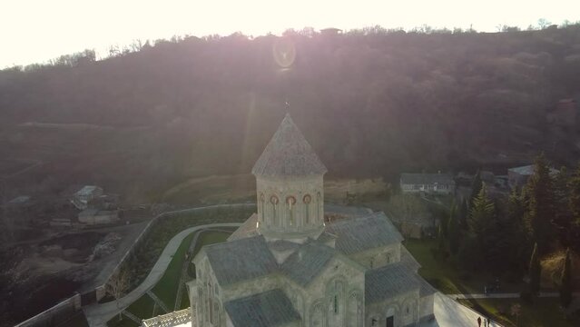 Scenic aerial view of monastic complex of Bodbe nunnery on hillside among tall Cypress trees with Church of St. Nino on sunny day, Sighnaghi, Georgia
