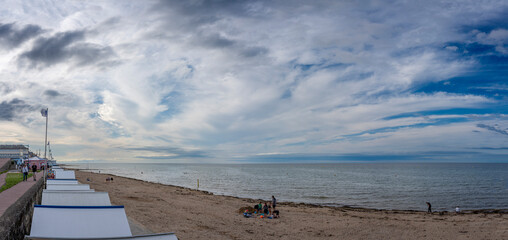 Langrune-Sur-Mer, France - 07 28 2023:  View of the roofs of beach cabins along the jetty from the beach at sunset with a cloudy sky.